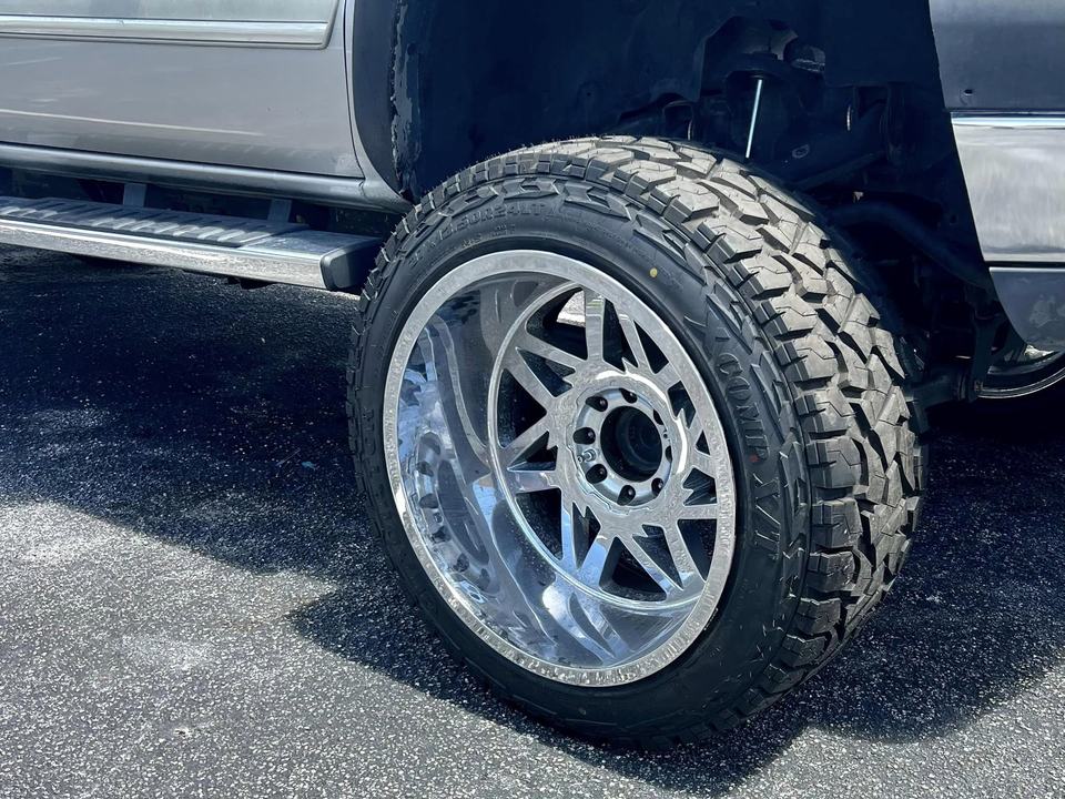 A lifted truck on large polished aftermarket wheels and mud-terrain tires