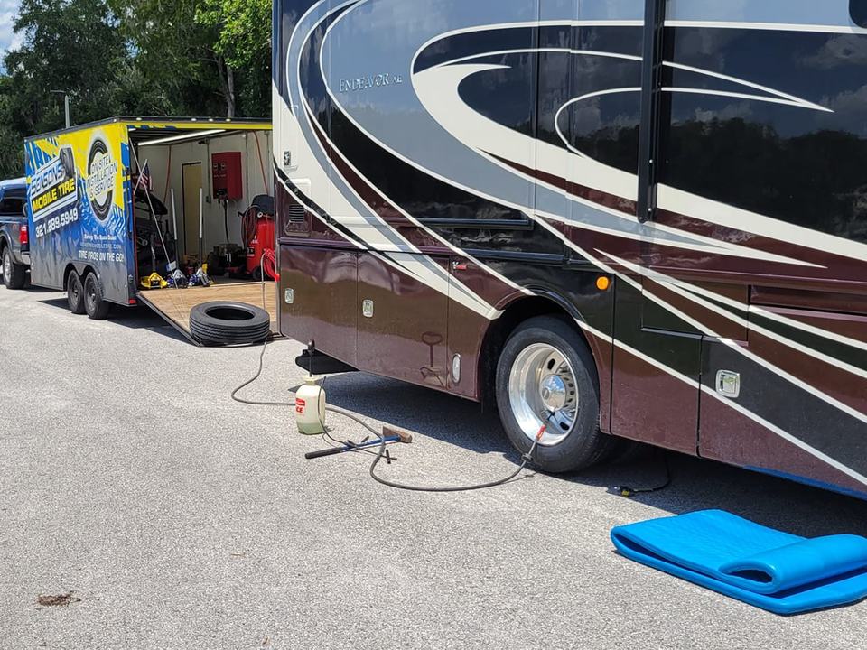 A Class A motorhome with an air line run to its rear tire, the Seasons trailer parked behind it