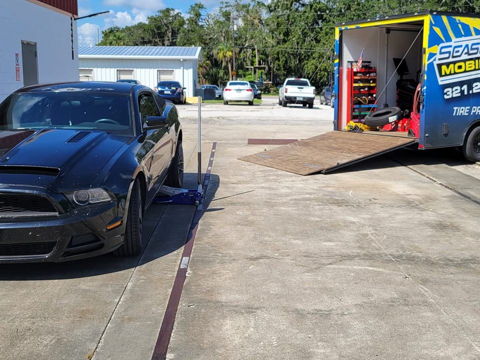 A black Ford Mustang on a jack beside the Seasons trailer ramp