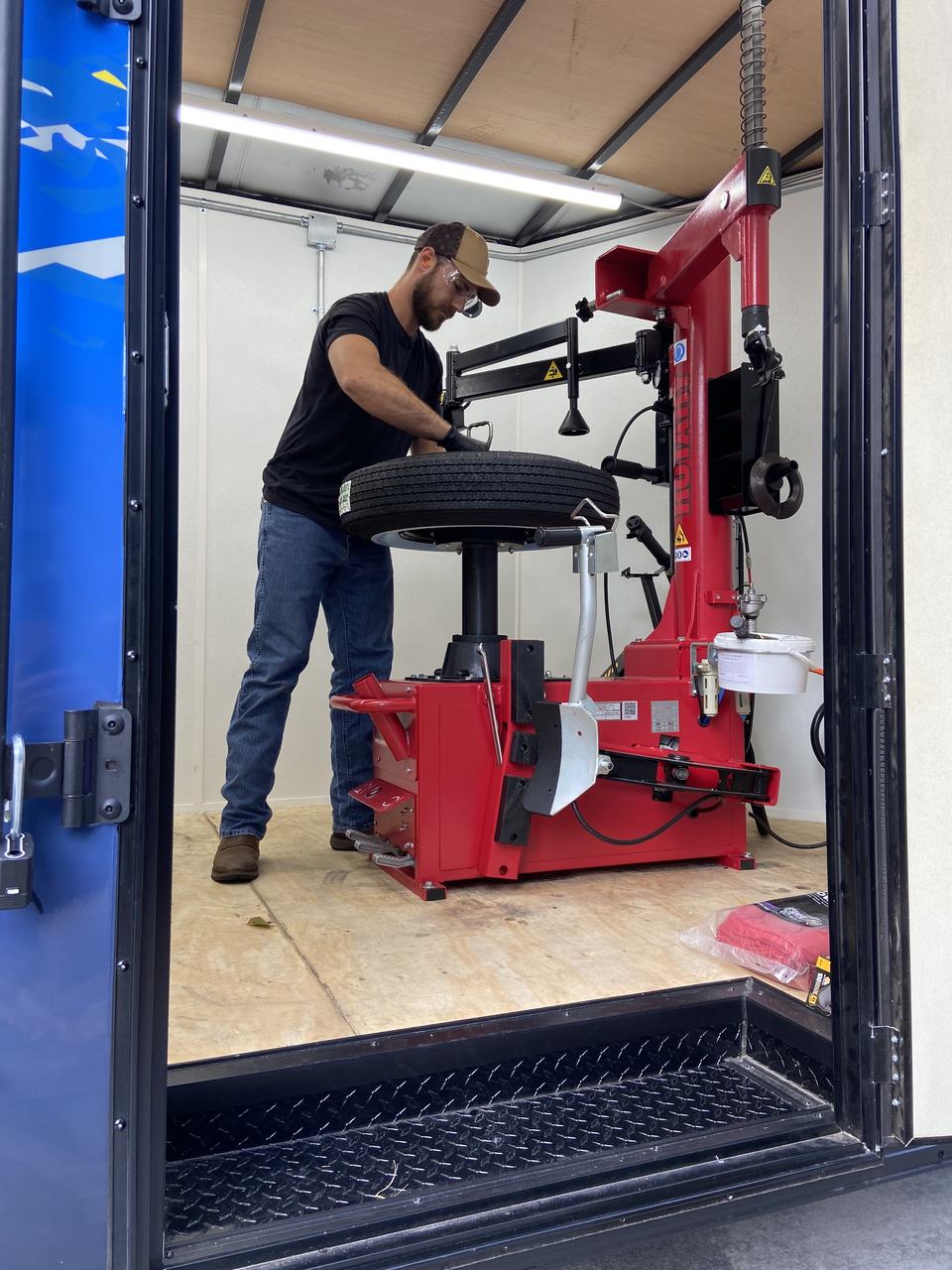 Rich Eckhardt mounting a tire on the tire changer inside the Seasons Mobile Tire trailer