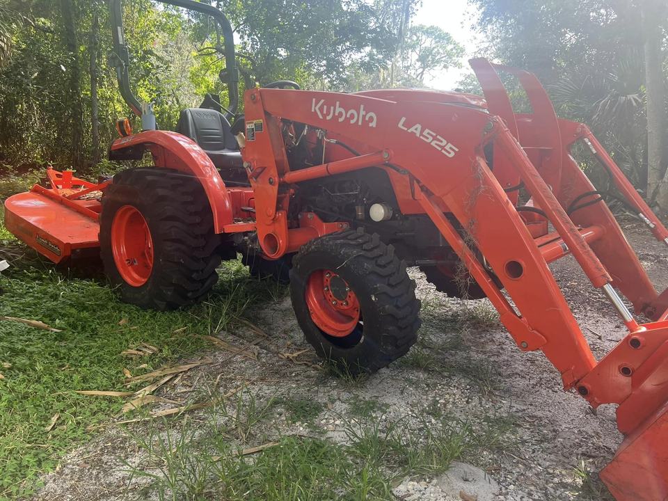 An orange Kubota tractor with a front loader, parked on grass